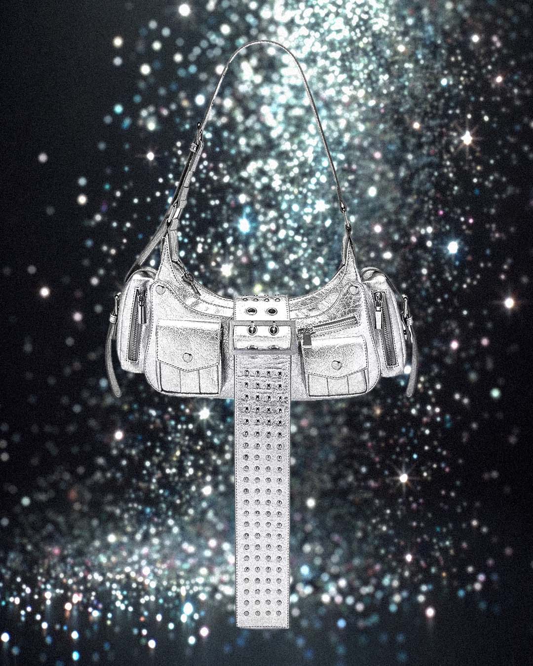 Silver handbag with a long strap on a sparkling black background